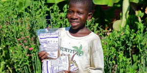 a boy holding " Impact Lives" Bags full of food