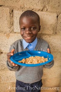 Little boy smiling with plate full of rice and beans