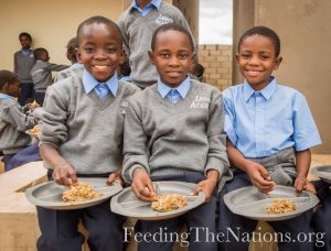 Three boys eating Rice and beans