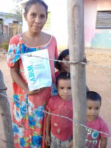 a mom holding a bag of rice standing next to her children